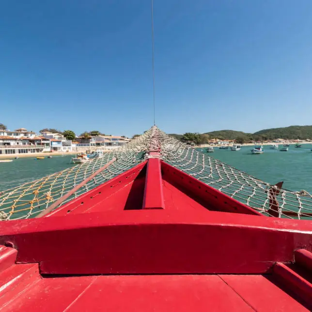 Proa de escuna vermelha navegando em direção à orla de Búzios