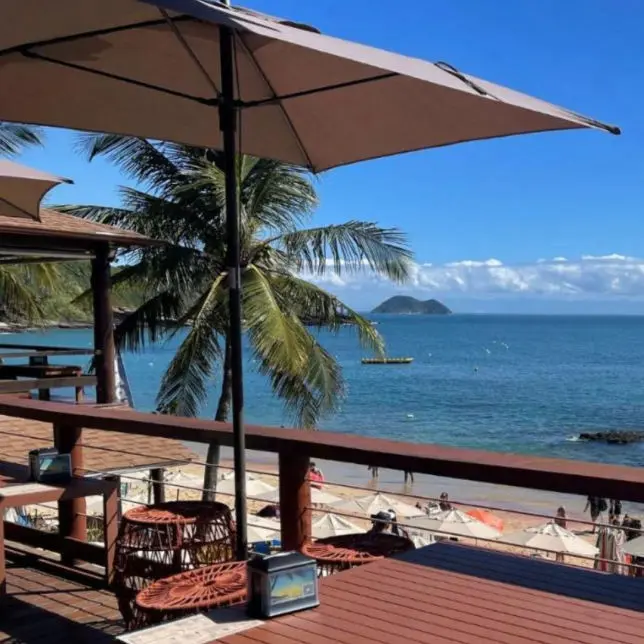 Trecho de praia em Búzios com águas calmas e vegetação na orla