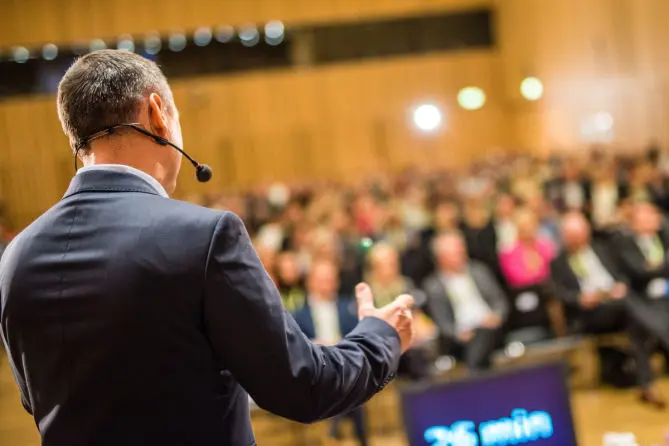 Palestrante conduzindo apresentação para plateia em auditório de congresso em Búzios