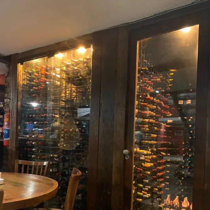 Adega de vinhos iluminada ao lado das mesas do restaurante Buzin em Búzios